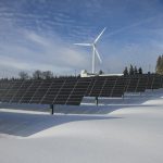 Solar Panels on Snow With Windmill Under Clear Day Sky
